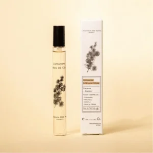 Perfume bottle with a black cap beside its white box, both featuring a pine botanical illustration and the fragrance name Coriandre & Bois de Cèdre