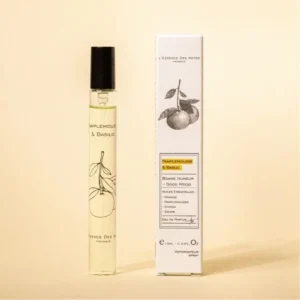 Vial of pale yellow perfume next to a tall white box with a citrus illustration and text reading Pamplemousse & Basil.